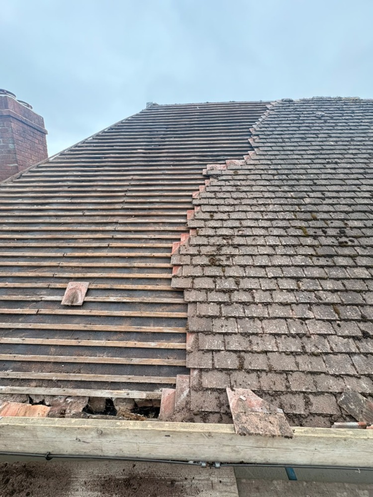 Roof half stripped showing old tiles and new battens